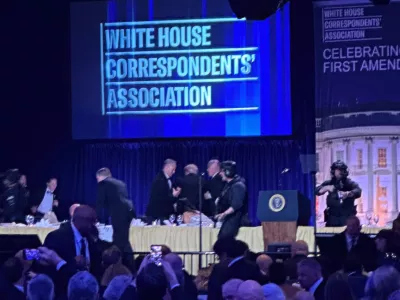 U.S. Secret Service agents surround President Donald Trump as he is taken from the stage after a shooting incident outside the ballroom during the White House Correspondents Dinner, Saturday, April 25, 2026, in Washington. (AP Photo/Alex Brandon)