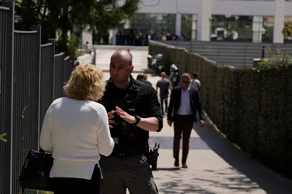 A policeman speaks with a woman outside a courthouse after a gunman opened fire leaving several people wounded in Athens, Tuesday, April 28, 2026. (AP Photo/Petros Giannakouris)
