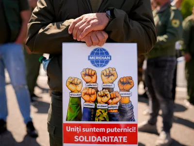 A man rests his hands on a placard reading "United we're strong! Solidarity" during a protest staged by multiple unions demanding the Government's resignation following measures in areas like taxation, work legislation and social security, outside the Government headquarters in Bucharest, Romania, Tuesday, April 28, 2026. (AP Photo/ Vadim Ghirda)
