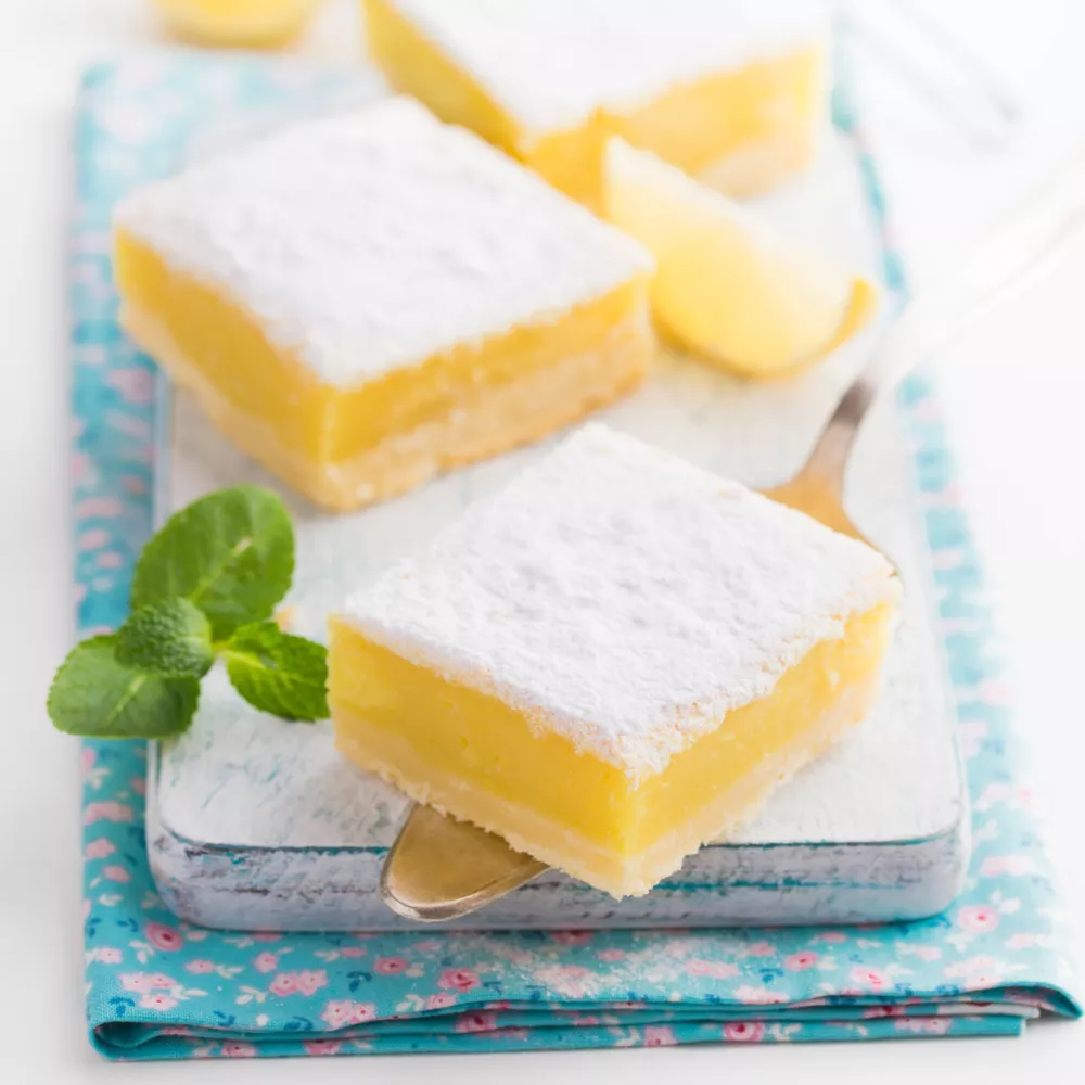 freshly baked lemon bars (or lemon squares) with powdered sugar on white bakground, selective focus / Foto: Anna_shepulova