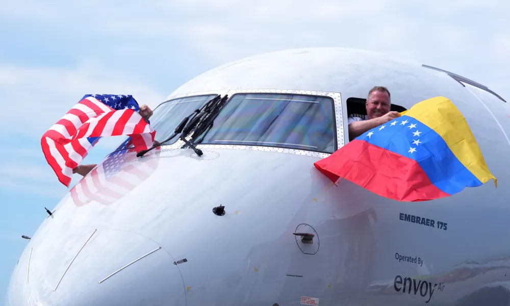Capt. Ric Wilson waves a Venezuelan flag and the first officer waves a U.S. flag as they prepare to fly American Airlines Flight AA3599, the first direct commercial flight between the United States and Venezuela in seven years, Thursday, April 30, 2026, at Miami International Airport in Miami. (AP Photo/Rebecca Blackwell)