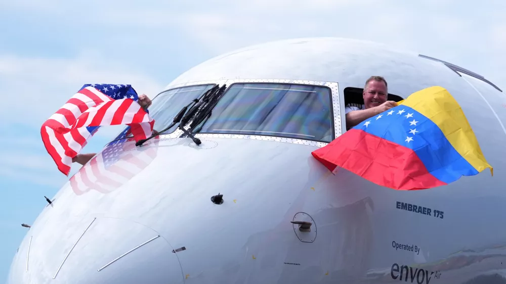 Capt. Ric Wilson waves a Venezuelan flag and the first officer waves a U.S. flag as they prepare to fly American Airlines Flight AA3599, the first direct commercial flight between the United States and Venezuela in seven years, Thursday, April 30, 2026, at Miami International Airport in Miami. (AP Photo/Rebecca Blackwell)