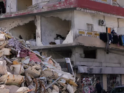 A woman hangs laundry in her damaged apartment after returning home with her family in the southern port city of Tyre, Lebanon, Thursday, April 30, 2026. (AP Photo/Hussein Malla)
