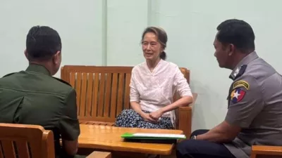 In this updated photo provided on April 30, 2026, by Myanmar Military True News Information Team, Myanmar's former leader Aung San Suu Kyi, center, talks with officials, in undisclosed location in Myanmar. (Myanmar Military True News Information Team via AP)