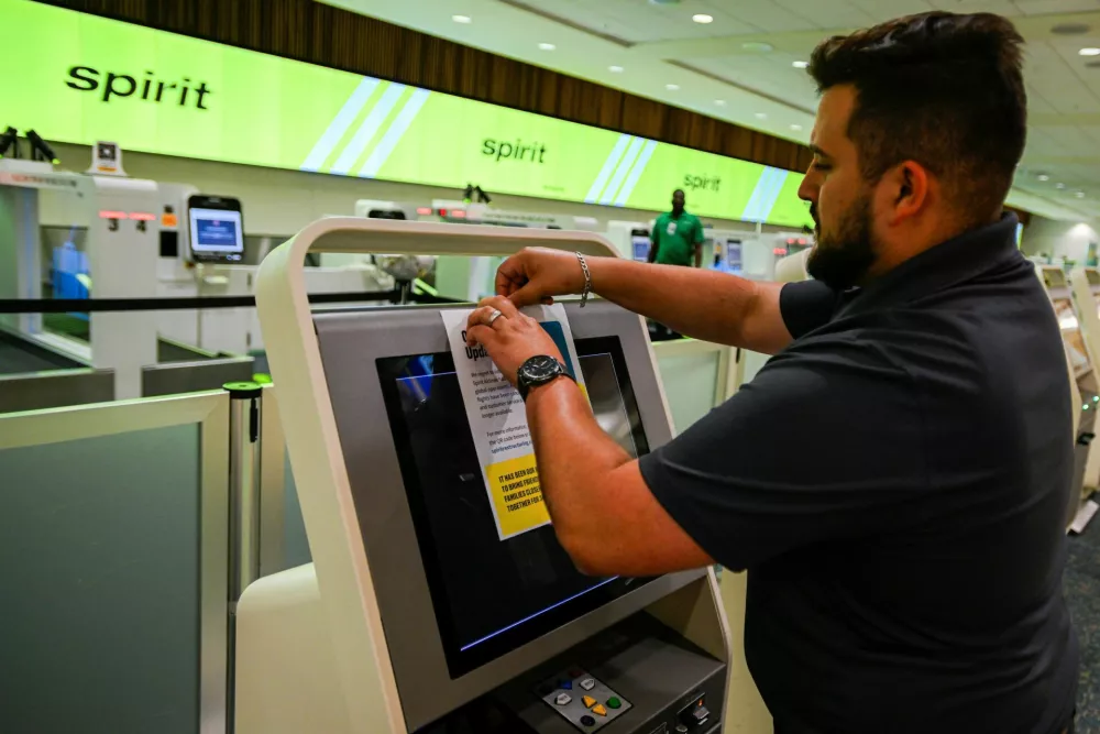 An employee sticks a Spirit Airlines operational update notice at Orlando International Airport, as the airline announced it was ceasing operations early Saturday morning following an impasse in talks with some creditors on a $500 million government bailout plan, in Orlando, Florida, U.S., May 2, 2026. REUTERS/Miguel Rodriguez