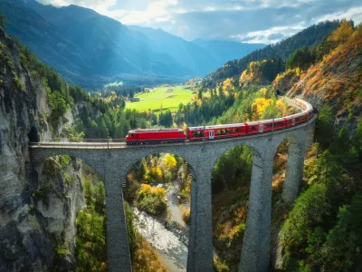 Aerial view of modern red train on Landwasser viaduct in alpine mountains, colorful forest at sunset in autumn. Bernina Express, Switzerland. Top view of train in Alps, railroad, green trees in fall,Image: 1003820041, License: Royalty-free, Restrictions:, Model Release: yes