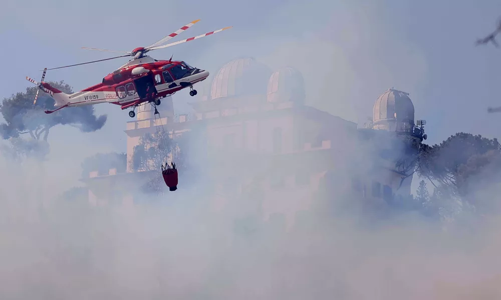 31 July 2024, Italy, Rome: A fire-fighting helicopter tries to extinguish the fire near the courthouse in the Monte Mario area. Photo: Cecilia Fabiano/LaPresse via ZUMA Press/dpa