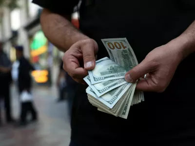 A currency dealer holds one-hundred-dollar bills, as the value of the Iranian rial drops, in Tehran, Iran, May 2, 2026. Majid Asgaripour/WANA (West Asia News Agency) via REUTERS ATTENTION EDITORS - THIS PICTURE WAS PROVIDED BY A THIRD PARTY