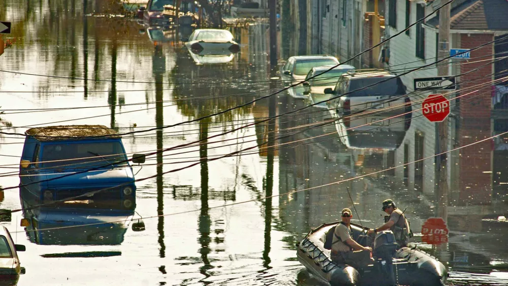 Two emergency personnel slowly cruise up a flooded street in New Orleans on Sunday, Sept. 4, 2005, six days after Hurricane Katrina devastated much of the gulf coast. Some residents have decided to remain, even as they are surrounded by floodwaters. (AP Photo/The Baltimore Sun, Karl Merton Ferron)