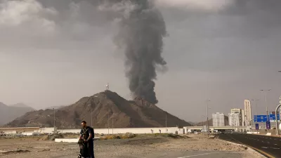 FILE PHOTO: A person rides on a scooter as smoke rises in the Fujairah oil industry zone following a fire caused by debris after interception of a drone by air defenses, in Fujairah, United Arab Emirates, March 3.  REUTERS/Amr Alfiky/File Photo