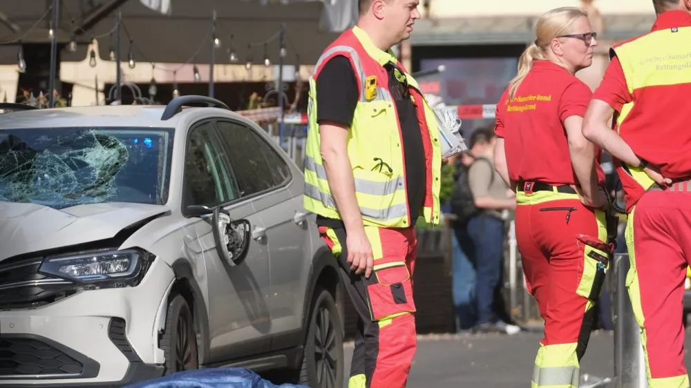 Rescue workers stand next to a damaged car that has crashed into several people in Leipzig, Germany, Monday, May 4, 2026. (Sebastian Willnow/dpa via AP)