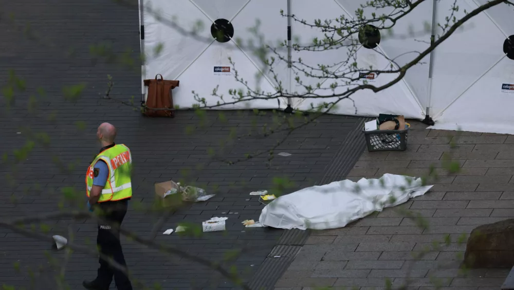 A policeman stands next to a body bag after a car crashed into several people in Leipzig, Germany, Monday, May 4, 2026. (Sebastian Willnow/dpa via AP)
