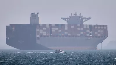 A container ship sits at anchor as a small motorboat passes in the foreground in the Strait of Hormuz off Bandar Abbas, Iran, Saturday, May 2, 2026. (Amirhosein Khorgooi/ISNA via AP)