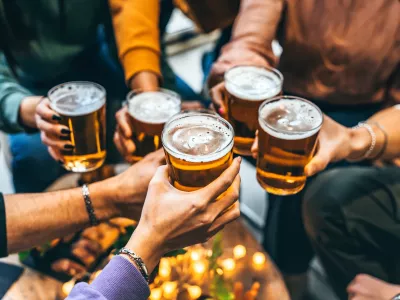 Group of friends drinking and toasting glass of beer at brewery pub restaurant- Happy multiracial people enjoying happy hour with pint sitting at bar table- Youth Food and beverage lifestyle concept