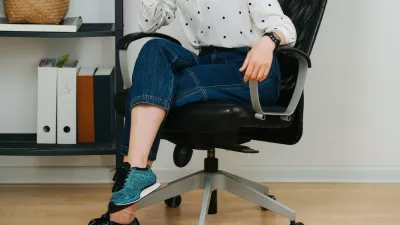 Posing woman in a desk chair at home smiling at the camera. She has her hair in a top knot, legs crossed, wearing short jeans.,Image: 718363309, License: Royalty-free, Restrictions:, Model Release: no