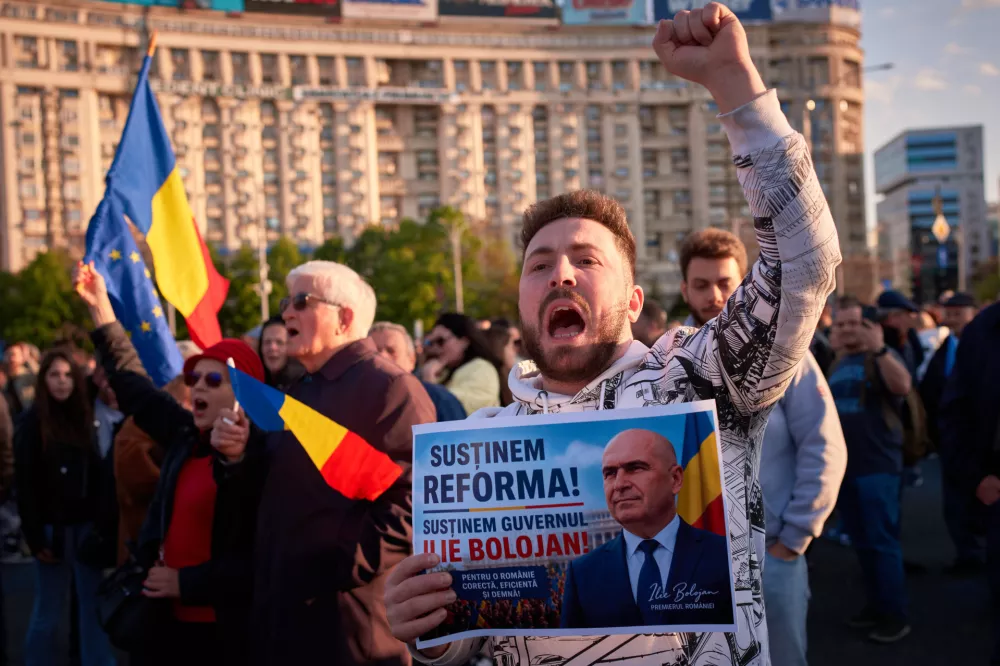 A man holding a poster that reads "We support the reform - We support the Bolojan cabinet" shouts during a rally in support of Romanian Premier Ilie Bolojan in Bucharest, Romania, Sunday, May 3, 2026. ahead of a no confidence vote on May 5. (AP Photo/Vadim Ghirda)