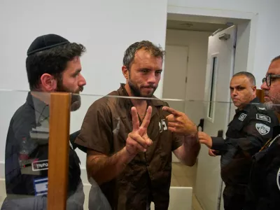 Brazilian activist Thiago &Aacute;vila, center, a member of the Global Sumud Flotilla, is escorted by prison service guards to a hearing at the District Court in Ashkelon, Israel, on Sunday, May 3, 2026. (AP Photo/Ohad Zwigenberg)