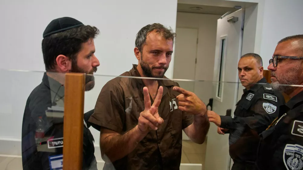 Brazilian activist Thiago &Aacute;vila, center, a member of the Global Sumud Flotilla, is escorted by prison service guards to a hearing at the District Court in Ashkelon, Israel, on Sunday, May 3, 2026. (AP Photo/Ohad Zwigenberg)