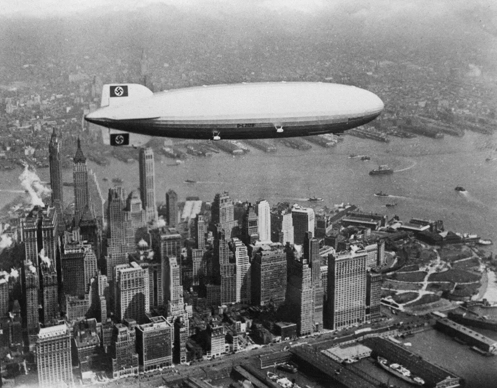 Image dated of the 30's showing German giant airship Hindenburg flying over Manhattan island in New York. Pride of the German Third Reich, the Hindenburg, the largest aircraft ever built, burst into flames 06 May 1937, 200 feet over its intended landing spot at New Jersey's Lakehurst Naval Air Station, killing 35 of its 97 passengers, along with one crewman on the ground.,Image: 17445017, License: Rights-managed, Restrictions:, Model Release: no