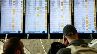 People look at departures screens showing delayed and cancelled flights at Amsterdam Airport Schiphol, as snowfall causes disruptions to air, rail and road traffic in the Netherlands, in Schiphol, Netherlands January 6, 2026. REUTERS/Piroschka van de Wouw / Foto: Piroschka Van De Wouw