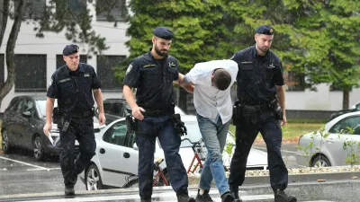 Emanuel Rep v spremstvu policistov na zasli&scaron;anje v Varaždinu. Sumijo ga umora mame s sekiro ter poskusa umorov polbrata in očima. 