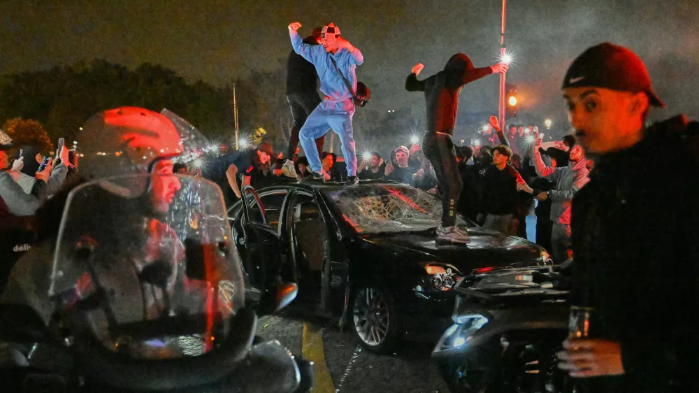People smash a car as they celebrate Paris Saint-Germain's Champions League semifinal victory over Bayern Munich at Place de la Concorde in Paris, Thursday, May 7, 2026. (AP Photo/Emma Da Silva)