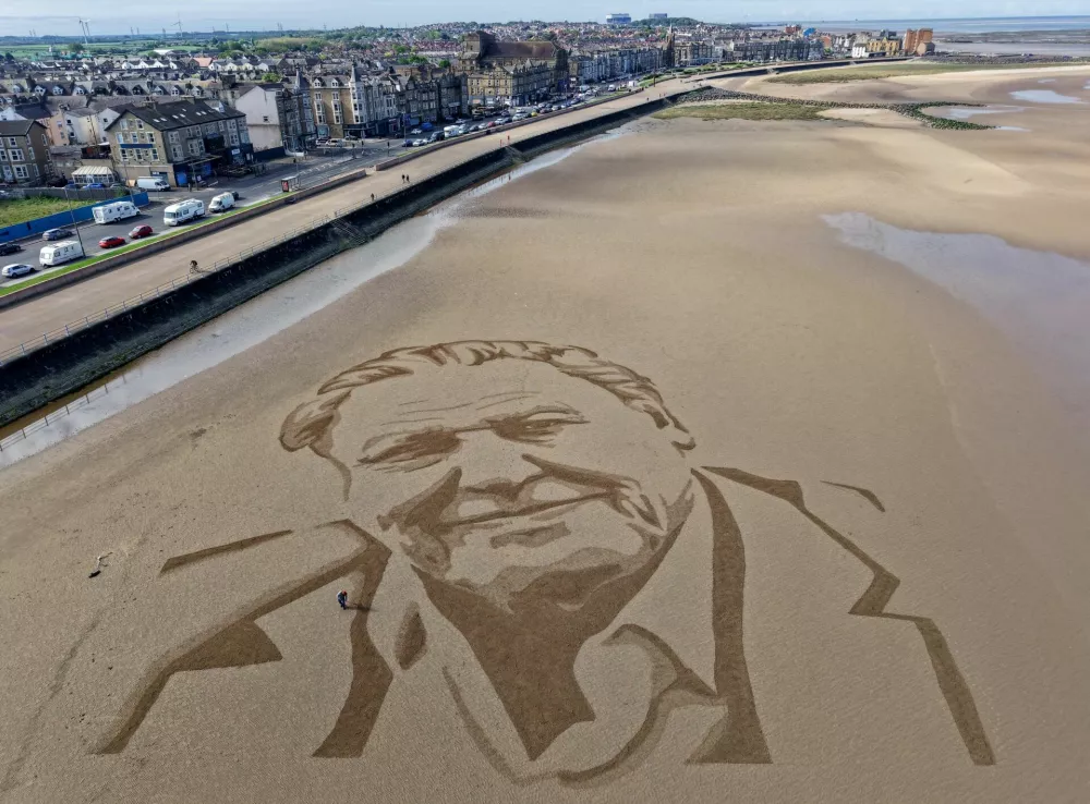 A drone view shows an artist from the Sand In Your Eye art team putting the finishing touches to a giant sand portrait of David Attenborough to mark the conservationist's 100th birthday, on the beach in Morecambe, Britain, May 6, 2026. REUTERS/Phil Noble