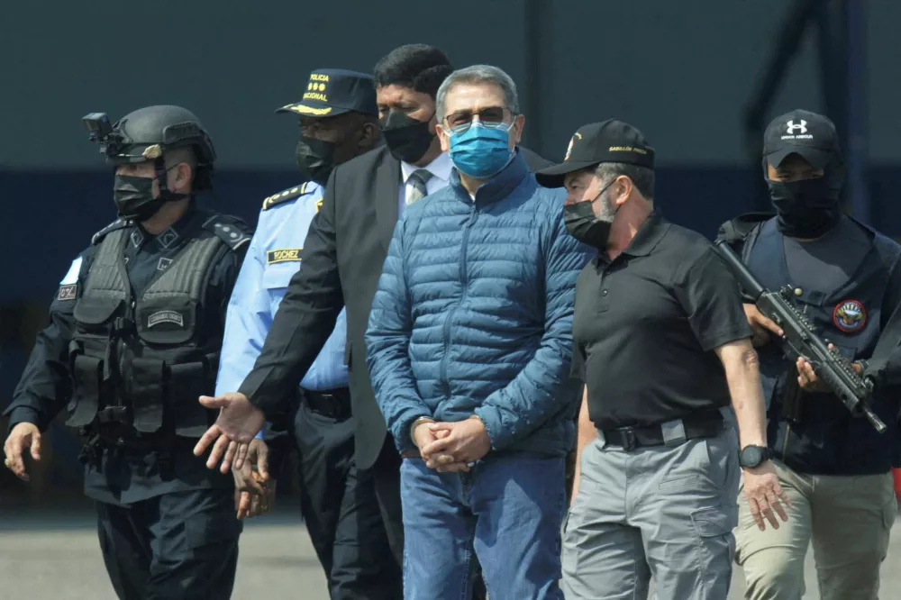 FILE PHOTO: Honduras former President Juan Orlando Hernandez is escorted by authorities as he walks towards a plane of the U.S. Drug Enforcement Administration (DEA) for his extradition to the United States, to face a trial on drug trafficking and arms possession charges, at the Hernan Acosta Mejia Air Force base in Tegucigalpa, Honduras April 21, 2022. REUTERS/Fredy Rodriguez/File Photo