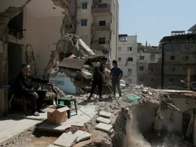 Ali Soueidan, 60, from southern Lebanon, looks at people cleaning his damaged house in the southern suburbs of Beirut, Lebanon, May 8, 2026. REUTERS/Raghed Waked