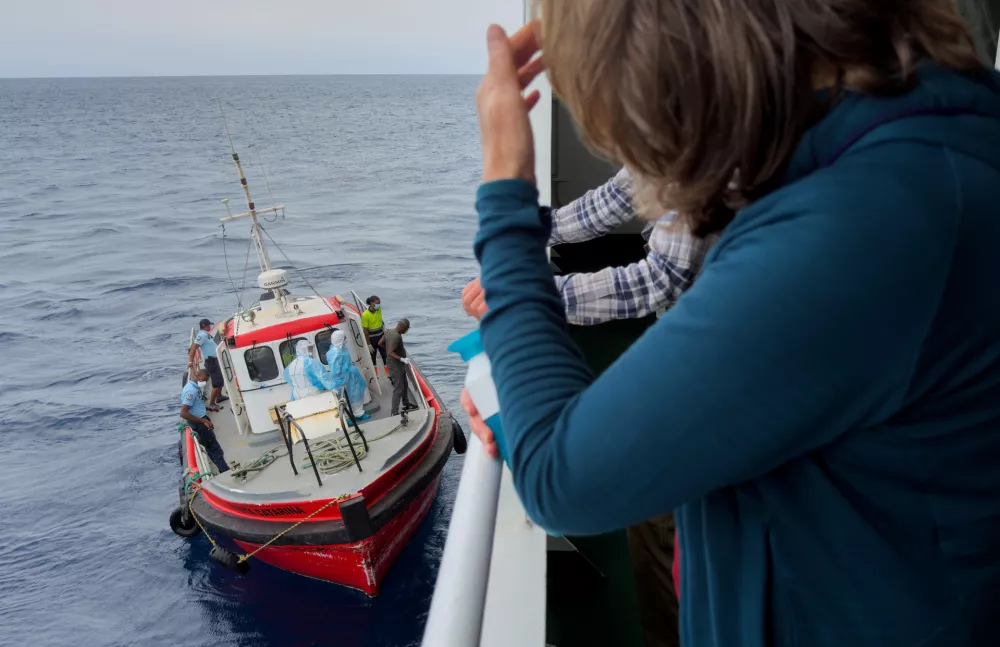 Passengers on the the hantavirus-stricken cruise ship, MV Hondius, watch epidemiologists board the boat in Praia, during their voyage to Spain's port of Tenerife, May 6, 2026. (AP Photo)