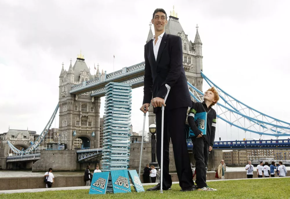 The world's tallest man, Sultan Kosen from Turkey, poses with a schoolboy for photographers at an event in London September 16, 2009. Kosen, who is 2 metres 46.5 cm (8 feet 1 inch) tall and also claims the record for the largest hands and largest feet, attended the event to promote the Guinness World Records 2010 book. REUTERS/Andrew Winning (BRITAIN SOCIETY)