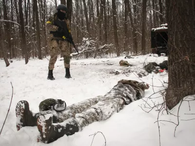 A volunteer of the Ukrainian Territorial Defense Forces looks at a dead body of a soldier lying in a forest in the outskirts of Kharkiv, Ukraine's second-largest city, Monday, March 7, 2022. Russia announced yet another cease-fire and a handful of humanitarian corridors to allow civilians to flee Ukraine. Previous such measures have fallen apart and Moscow&acirc;&euro;&trade;s armed forces continued to pummel some Ukrainian cities with rockets Monday. (AP Photo/Andrew Marienko).