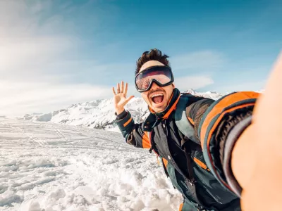 Happy skier taking a selfie on the mountains - Young man having fun skiing downhill in winter forest