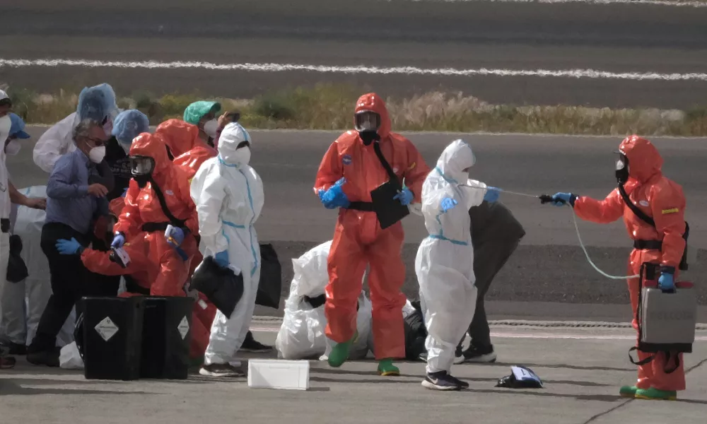 Passengers are sprayed with disinfectant by Spanish government officials before boarding a plane after disembarking from the hantavirus-stricken cruise ship MV Hondius at Tenerife airport in the Canary Islands, Spain, Sunday, May 10, 2026. (AP Photo/Arturo Rodriguez)