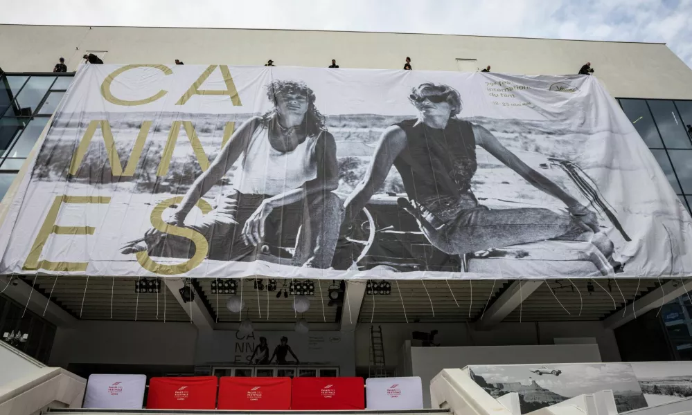 Workers set up a giant canvas of the official poster featuring actors Geena Davis and Susan Sarandon from Ridley Scott's road movie "Thelma & Louise" on the facade of the Festival palace before the start of the 79th Cannes Film Festival in Cannes, France, May 10, 2026. REUTERS/ Marko Djurica
