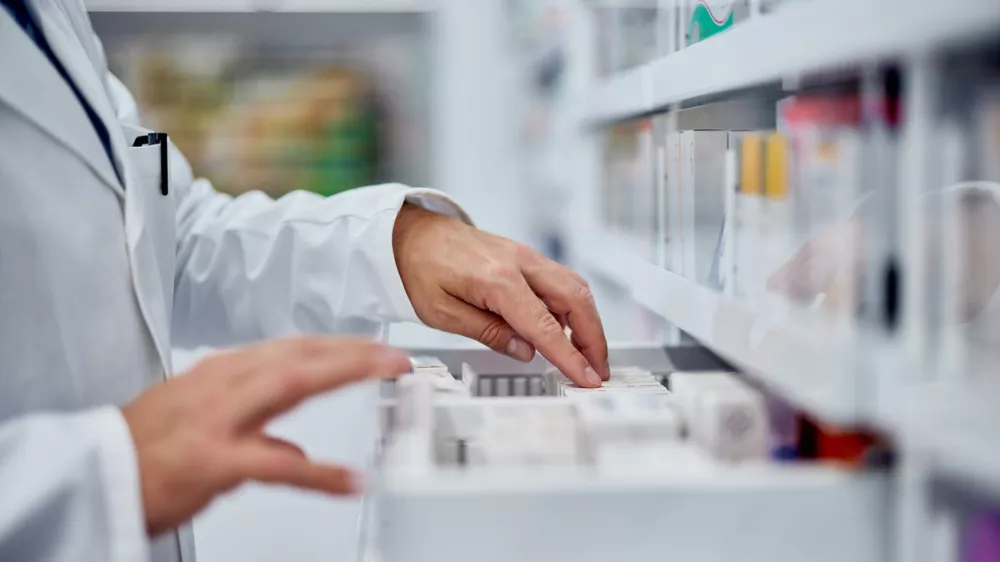 Male pharmacist choosing a medicine from the drawer, side view.