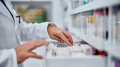 Male pharmacist choosing a medicine from the drawer, side view.