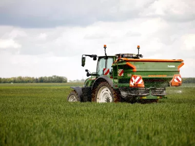 A French cereal farmer drives his tractor with a spinning-disc that spreads nitrogen fertilizer white pellets on a wheat field in Larchant, France, May 7, 2026. REUTERS/Alice Sacco