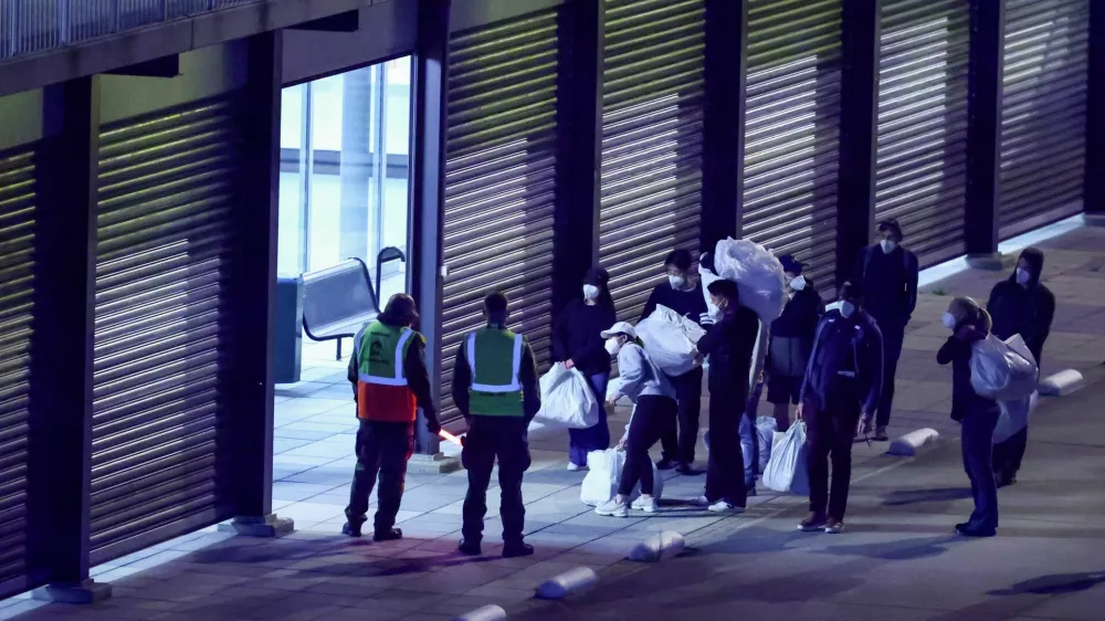 Passengers evacuated from the cruise ship MV Hondius, which was affected by a hantavirus outbreak, carry their belongings after disembarking at Eindhoven Air Base, Netherlands, May 12, 2026. REUTERS/Piroschka van de Wouw