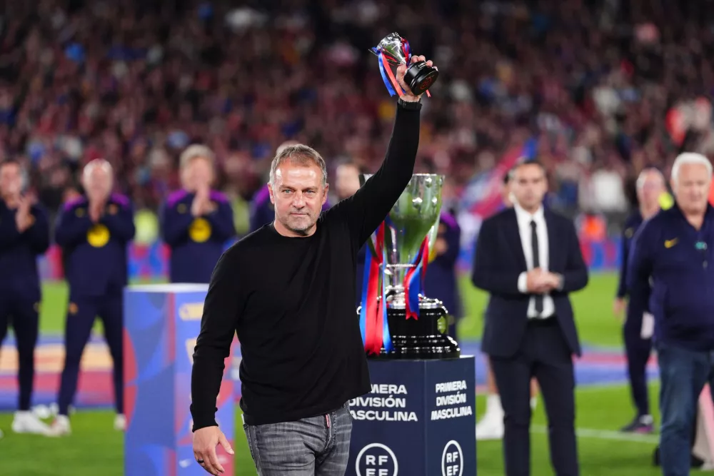 Barcelona head coach Hansi Flick lifts his award to the sky celebrating after defeating Real Madrid 2-0 to win the Spanish La Liga soccer championship with three rounds to spare, in Barcelona, Spain, Sunday, May 10, 2026. (AP Photo/Joan Mateu Parra)
