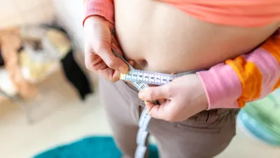 woman measures her abdomen with a measuring tape