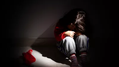 young girl sitting down alone in the dark.