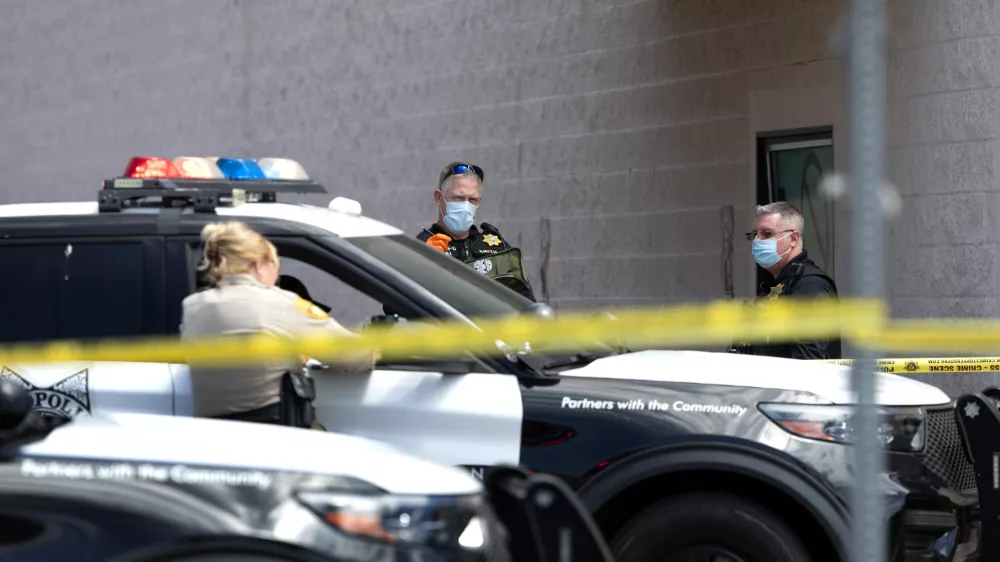 Las Vegas Metropolitan Police crime scene analysts and a Metro Police officer, left, work outside a Smith's supermarket in Las Vegas, after a reports of a shooting on Tuesday, May 12, 2026. (Steve Marcus/Las Vegas Sun via AP)