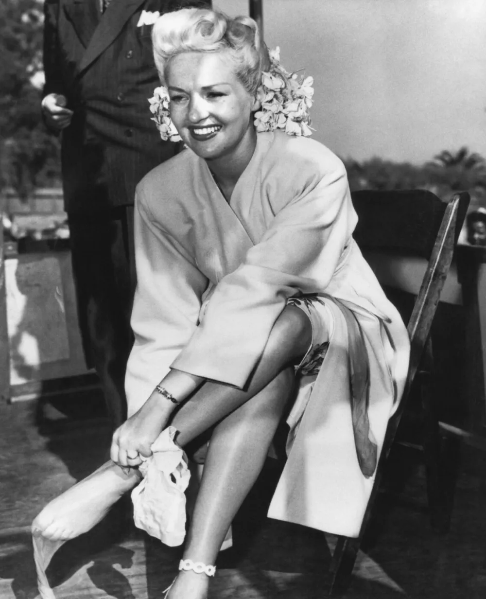 Betty Grable (1916-1973), US actress. Born Elizabeth Ruth Grable, she made her debut as a child actor in 1929. She rose to fame in the 1940s, appearing in a succession of musical films. Renowned for her beauty and her legs (which were insured by her film studio). She became a pin-up girl during World War II, and was known as 'the girl with the million dollar legs'. Here, her stockings, made of the new material nylon, are about to be auctioned at a World War II bond rally. Grable's stockings typically sold for around 40,000 US dollars a pair at such auctions. During the war, around 185 billion US dollars were raised through war bonds. Photographed circa 1942.,Image: 177935512, License: Rights-managed, Restrictions:, Model Release: no 