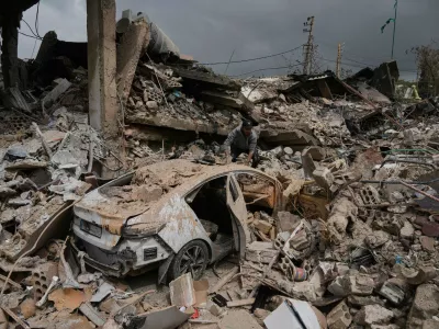 A man inspects his damaged car amid the rubble of shops destroyed in previous Israeli airstrikes in the Hosh neighborhood of Tyre, southern Lebanon, April 19, 2026. (AP Photo/Bilal Hussein)