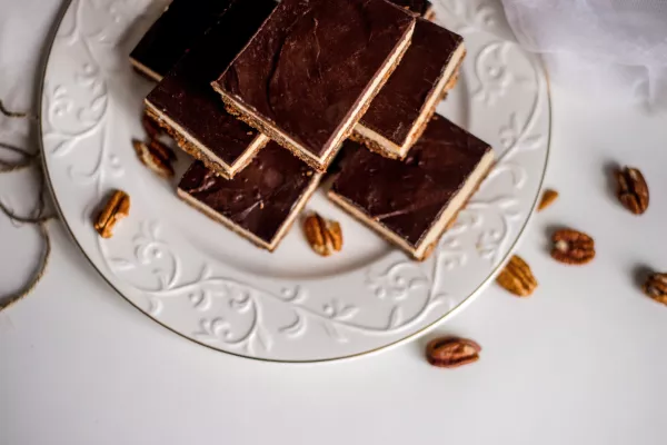 Very appetizing beautiful food photo of tasty chocolate authentic canadian dessert Nanaimo with nuts in healthy version - plant based and shugar free. Served on the elegant white plate on a white background. / Foto: Anton Parshunas