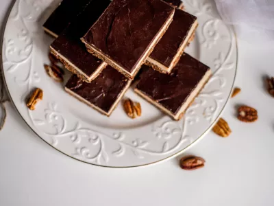 Very appetizing beautiful food photo of tasty chocolate authentic canadian dessert Nanaimo with nuts in healthy version - plant based and shugar free. Served on the elegant white plate on a white background. / Foto: Anton Parshunas