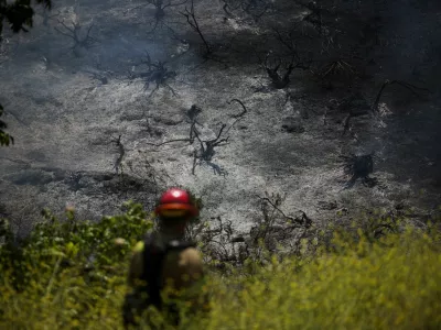 A firefighter walks towards a charred hillside during a wildfire known as the Sandy Fire, in Simi Valley, California, U.S., May 18, 2026. REUTERS/Daniel Cole   TPX IMAGES OF THE DAY / Foto: Daniel Cole