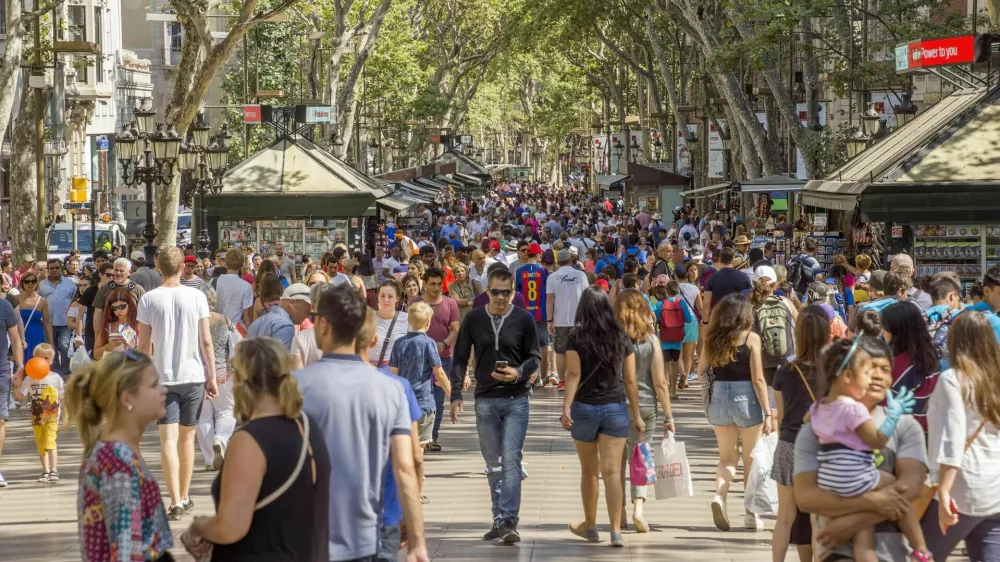 Barcelona, Spain - July 5, 2016: Hundreds of people promenading in the busiest street of Barcelona, the Ramblas. The street extends 1.2 kilometers connects the Placa de Catalunya in the centre with the Christopher Columbus Monument at Port Vell.