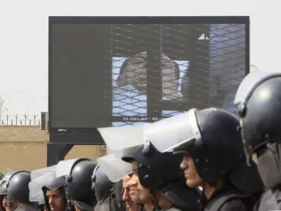 Egyptian anti-riot soldiers line up under a giant screen showing former President Hosni Mubarak outside the police academy court in Cairo, Egypt, Monday, Aug. 15, 2011. Former President Hosni Mubarak returned to court Monday for the second session of his trial on charges of corruption and complicity in killing protesters during the mass uprising that ousted him from power. (AP Photo/Amr Nabil)